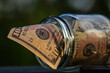 © Vlad Ispas - US dollar banknote saving money in glass jar. Consumption and economy