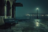 Empty bench sits on a desolate harbor at night, illuminated by a lone streetlight and shrouded in fog