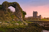Sunset over historical Dunguaire Castle landmark in Kinvara, Galway Ireland with stone arch in foreground,  architecture background