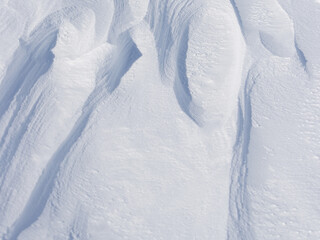Wall Mural - Snow texture. Wind sculpted patterns on snow surface. Wind in the tundra and in the mountains on the surface of the snow sculpts patterns and ridges (sastrugi). Arctic, Polar region. Winter background
