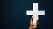 © Светлана Воротняк - African american hand holding a white christian cross against a solid dark background. Concept of faith, baptism, and spiritual devotion.