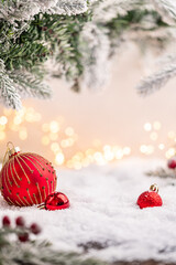 Wall Mural - red baubles rest on snowy ground beneath frosted pine branches with golden holiday lights in the bac