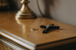 © ana - Black wooden cross and gold wedding ring on polished nightstand