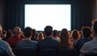 © Vadym - Audience observes large blank screen during presentation. People watch display in dark room. Group of attendees in seminar or conference. Pro business event with focus on tech or visual information.