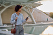 Businesswoman holding smartphone and walking in urban city with modern architecture in background