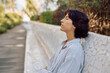 © we.bond.creations - Businesswoman taking a break from work, sitting on a bench with closed eyes, breathing fresh air and enjoying the peace of nature