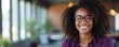 © Vadym - Smiling Black woman wearing glasses and purple shirt poses in modern office setting. She has curly hair and a friendly expression. Pro headshot with natural light.