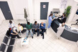 © DC Studio - Top view of nurse in blue scrubs and elderly doctor speaking with female hospital receptionist, updating medical records. Clinical lobby showing multiethnic patients preparing for health consultations