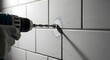 © Vektor Stokart - Drilling a hole into a tiled wall with a power drill and safety glove in a close up shot of the action