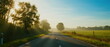 © Adobe Contributor - Sunlit Road with Trees and Green Fields in the Morning