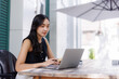 © crizzystudio - Businesswoman working on laptop in outdoor cafe