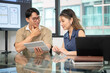 © bongkarn - Asian glasses man holding tablet and stylus pen talking to woman coworker in office's meeting room.