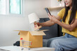 © wichayada - Online shopping. Woman taking a photo of a lamp after unboxing.