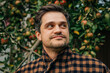 © Masson - stylish European man in a vintage brown wool blazer stands contemplatively by an apple tree