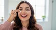 © Vom Baty - A happy young woman applies anti-aging gel to her face, demonstrating her daily skincare routine with a radiant smile, perfect for a beauty and health ad.