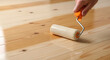 © fia - Applying a protective varnish layer to a new wooden plank floor with a paint roller for renovation
