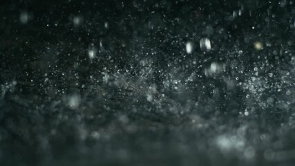 Wall Mural - Closeup of rain hitting dark surface in soft light, abstract wet textures form