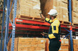 © ฺฺฺBoonterm - Black male salesperson wearing hard hat stands inspecting shelves using barcode reader digital to scan boxes of goods that are neatly stored to quickly and accurately check the inventory information.