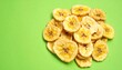 © DeepGrid  - Dehydrated Banana Chips: A vibrant shot of dehydrated banana chips on a lively green backdrop, emphasizing texture and visual appeal of snack food.