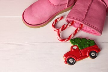 Wall Mural - Saint Nicholas day. Boots with candy canes and cookie in shape of car on white wooden table, flat lay. Space for text
