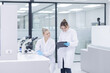 © charnsitr - Scientists collaborate in a modern laboratory, sharing results and analyzing data on a tablet