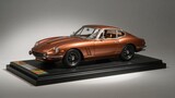 Classic brown vintage sports car on display stand with black wheels and tan interior under studio lighting