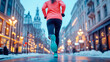 © sommersby - Dedicated runner in bright orange jacket navigates beautifully lit, snow-dusted city street at dusk, showcasing winter urban fitness.