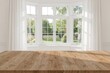 © Giovanni - Image of an empty high-quality teak tabletop ready for product placement, bathed in beautiful sunlight streaming through a bright bay window, with a garden scene and flowing translucent curtains in
