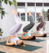 © JackF - Group of women taking care of their physical health and doing yoga in a fitness center perform an exercise standing in a pose .with their legs raised during a workout