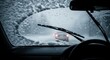 © MMerellinn - Sudden heavy snowfall creates dangerous driving conditions on icy road. Car windshield wipers struggle to clear thick accumulating snow and freezing rain.