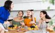 © JackF - Group of women friends talking and drinking wine at party in kitchen