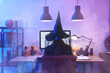 © Pixel-Shot - Woman dressed for Halloween as witch using computer at table in dark office, back view