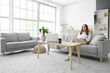 © Pixel-Shot - Young woman sitting on sofa with air humidifier at home