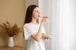 © Pixel-Shot - Young woman eating salad in stylish room