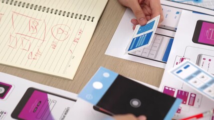 Panorama video of startup UX developer or company employee design user interface or UI prototype for mobile application or website software with software display on smartphone in office. Synergic