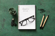 © Pixel-Shot - Notebook with text GOALS 2026 and eyeglasses on green grunge table