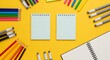 © Ilham - Creative flat lay with two blank notebooks, markers, colorful pencils, and sketchbooks on a yellow background, flat lay style representing art supplies.
