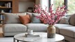 © melano - Elegant pink cherry blossom branches brighten a cozy living room with a modern sofa and marble table