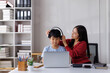 © Phimwilai - Asian mother helping son wearing headphones for online class at home