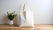 © Yshfrn - Off white Tote Bag Mockup with Green Plant on Wooden Table