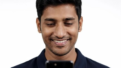 Young Man Smiles While Using His Mobile Phone on a White Background in the Studio