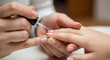 © fia - Closeup of a manicurist applying pink nail polish to a woman's fingernail in a salon