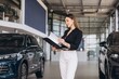 © anatoliycherkas - Woman reviewing car purchase documents in dealership
