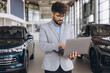 © anatoliycherkas - Arab businessman using laptop in car dealership