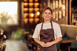 © bnenin - Smiling Female Barista Standing In a Cozy and Beautifully Lit Café Interior