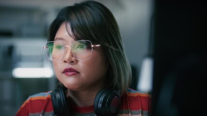Young Asian Female Tech Developer and Computer Programmer using desktop computer typing on keyboard, writing code, developing software application and reviewing code sit at desk in modern Tech office.