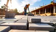 © Dafnia - A construction worker lays paving stones on a sunny day. Other workers and building structures are visible