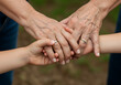 © nanda - A touching close-up of three generations of hands, from child to grandmother, clasped together in a symbol of family love, unity, and support