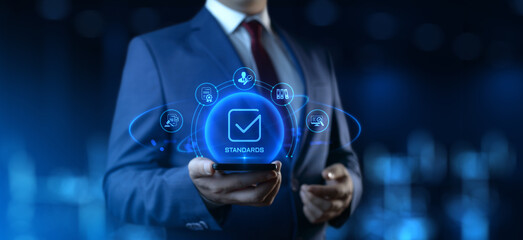 Wall Mural - businessman holding smartphone with standards icons on screen. quality management concept