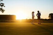© Drazen - Full length of golf partners playing on golf course at sunset.